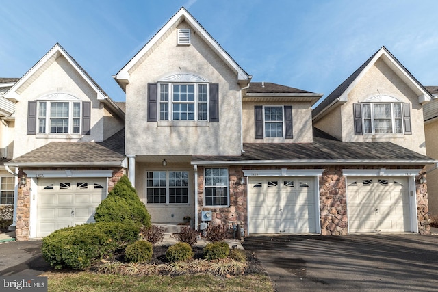 traditional-style home featuring aphalt driveway, an attached garage, and stucco siding