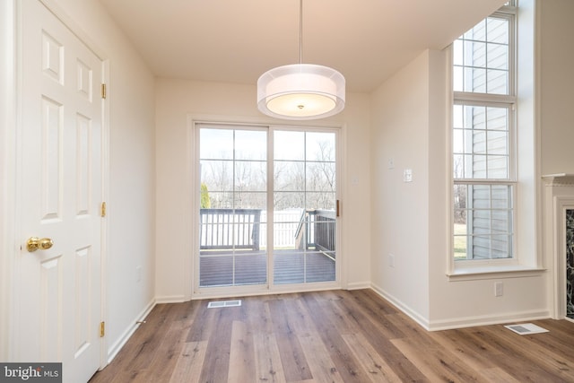 unfurnished dining area with visible vents, baseboards, and wood finished floors