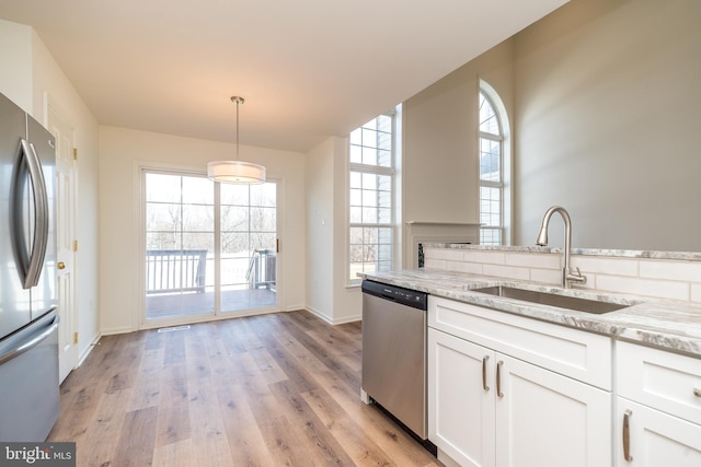 kitchen featuring a sink, light wood-style flooring, appliances with stainless steel finishes, and white cabinets