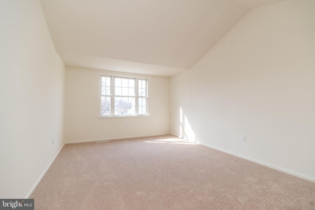 carpeted empty room with baseboards and lofted ceiling