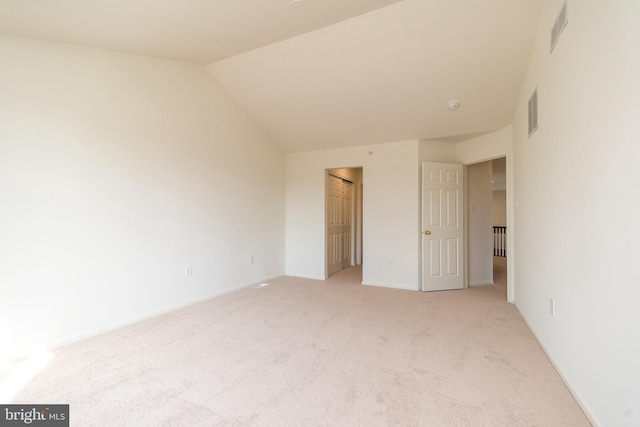 unfurnished bedroom with light carpet, visible vents, a closet, and lofted ceiling