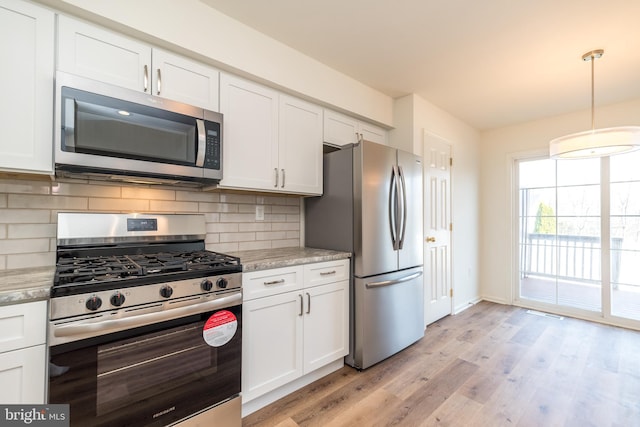 kitchen featuring backsplash, appliances with stainless steel finishes, white cabinetry, and light wood-style flooring