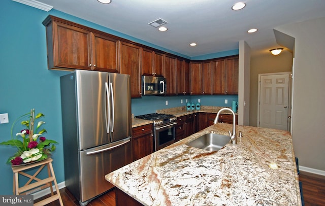 kitchen featuring visible vents, dark wood-type flooring, light stone counters, appliances with stainless steel finishes, and a sink