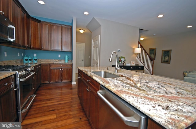 kitchen featuring light stone countertops, recessed lighting, appliances with stainless steel finishes, dark wood-style floors, and a sink