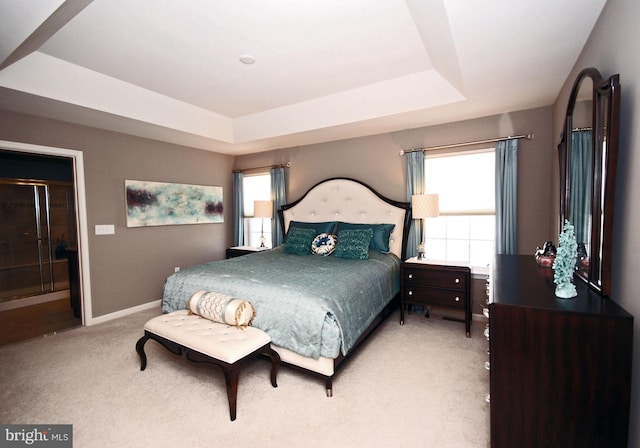 carpeted bedroom featuring a tray ceiling and baseboards