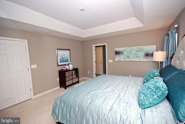 carpeted bedroom with a tray ceiling, visible vents, and baseboards