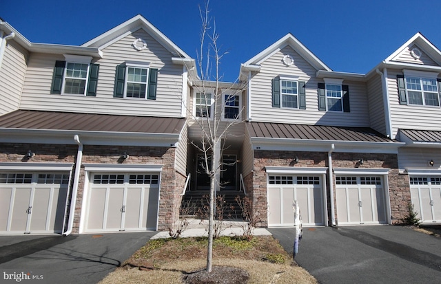 multi unit property with stone siding, driveway, and a standing seam roof