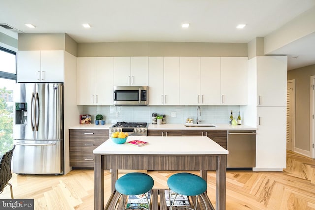 kitchen featuring a sink, light countertops, tasteful backsplash, and stainless steel appliances