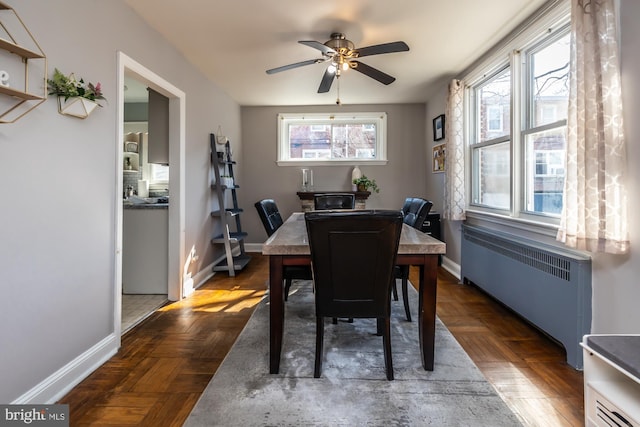 dining area featuring baseboards, ceiling fan, and radiator heating unit