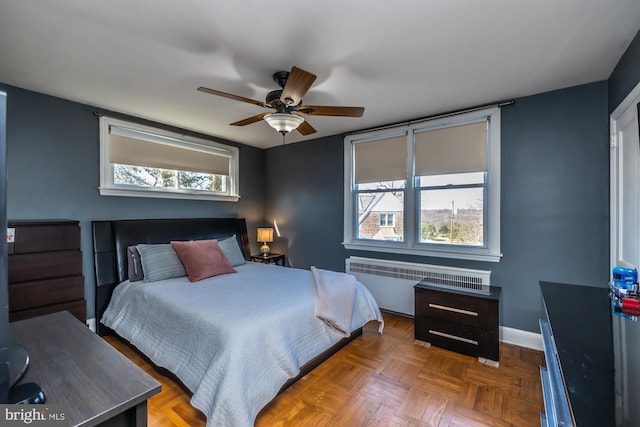 bedroom with baseboards, multiple windows, radiator, and ceiling fan