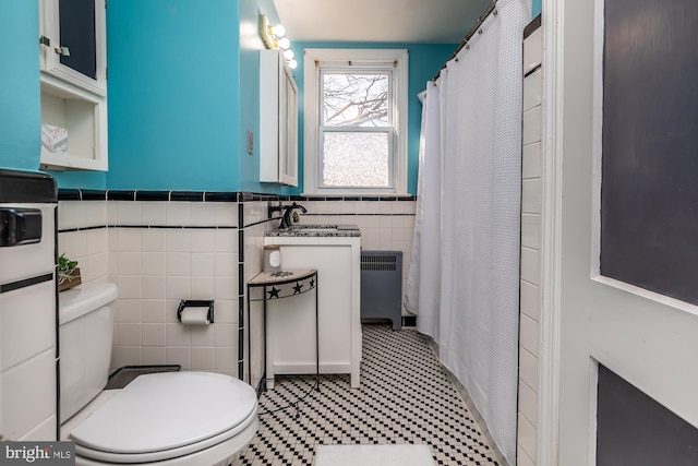 full bathroom with curtained shower, radiator, toilet, wainscoting, and tile walls