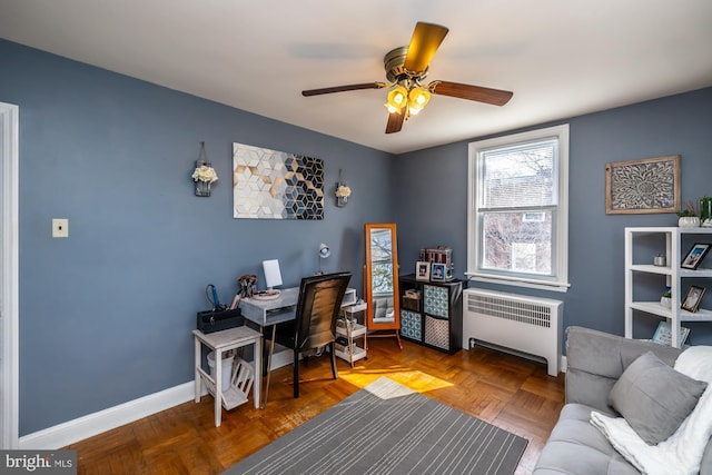 office area with baseboards, a ceiling fan, and radiator heating unit