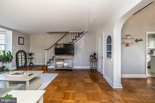 entrance foyer featuring baseboards, arched walkways, and stairs