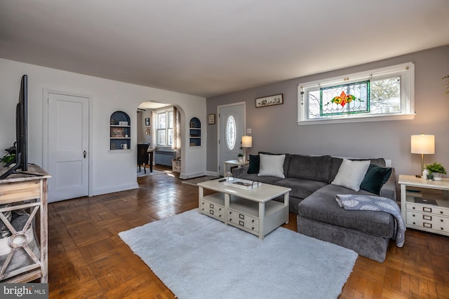 living room featuring arched walkways and baseboards