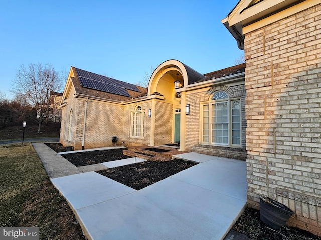 property entrance with roof mounted solar panels and brick siding