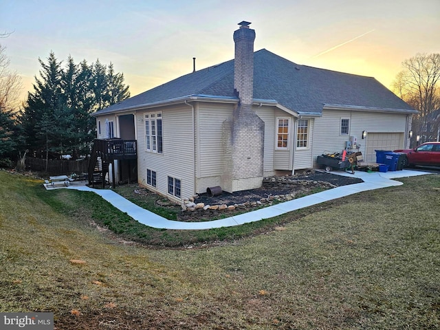 property exterior at dusk featuring stairway, a lawn, a chimney, and a garage