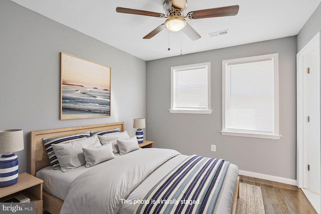 bedroom with visible vents, ceiling fan, baseboards, and wood finished floors