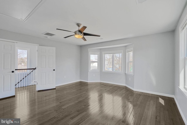 unfurnished room featuring a wealth of natural light, dark wood-type flooring, and attic access