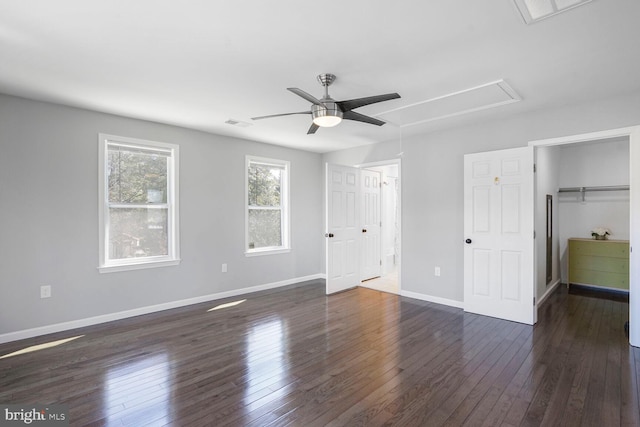 unfurnished bedroom with visible vents, baseboards, attic access, dark wood-type flooring, and a spacious closet