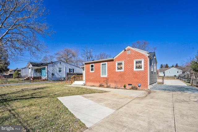 back of property featuring fence, a yard, concrete driveway, crawl space, and brick siding