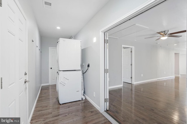 hallway featuring visible vents, baseboards, attic access, stacked washing maching and dryer, and wood finished floors