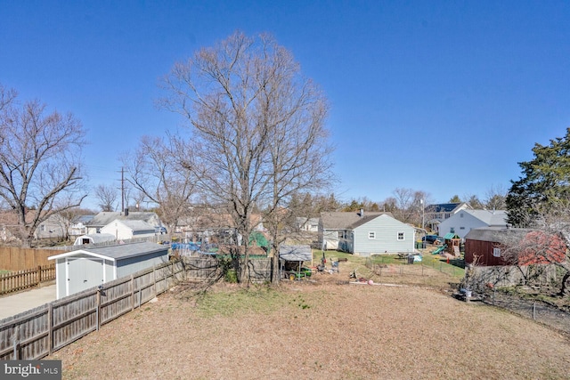 view of yard with a fenced backyard, a residential view, a storage unit, and an outdoor structure