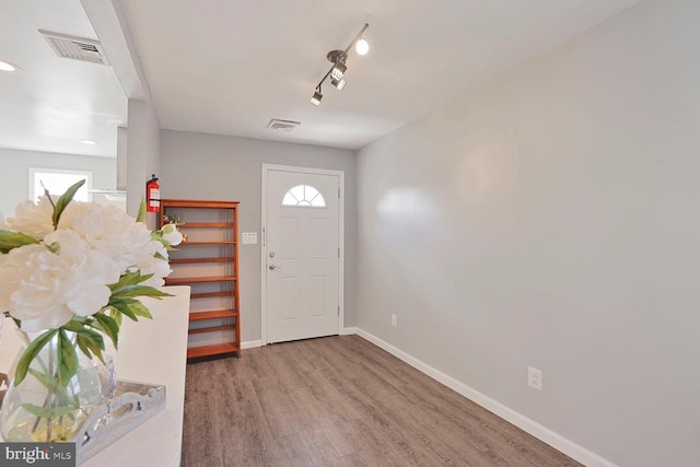 foyer with a healthy amount of sunlight, wood finished floors, visible vents, and baseboards