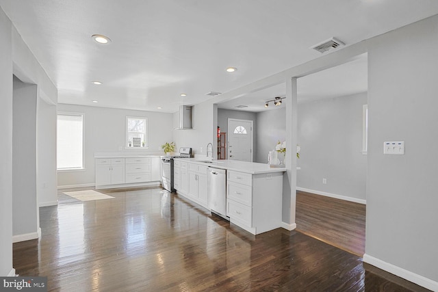 kitchen with visible vents, baseboards, appliances with stainless steel finishes, a peninsula, and dark wood-style flooring