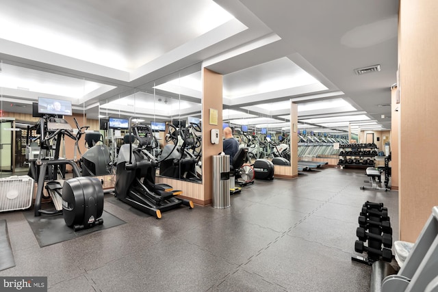 exercise room with visible vents and a tray ceiling