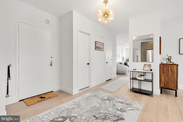 foyer with a chandelier, baseboards, and light wood-style flooring