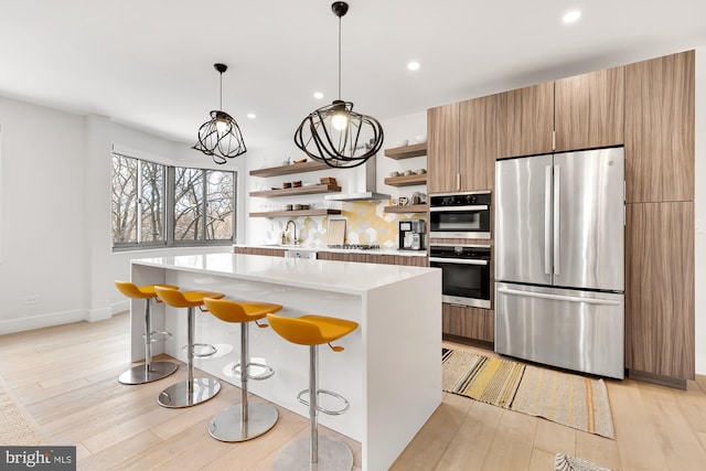 kitchen featuring a kitchen island, open shelves, stainless steel appliances, light countertops, and light wood-type flooring