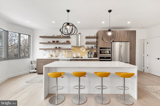 kitchen featuring light countertops, appliances with stainless steel finishes, modern cabinets, wall chimney exhaust hood, and open shelves