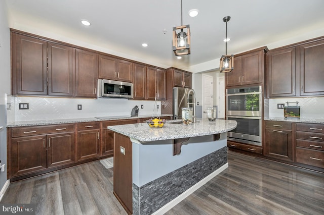 kitchen featuring decorative backsplash, dark wood-type flooring, appliances with stainless steel finishes, and a sink