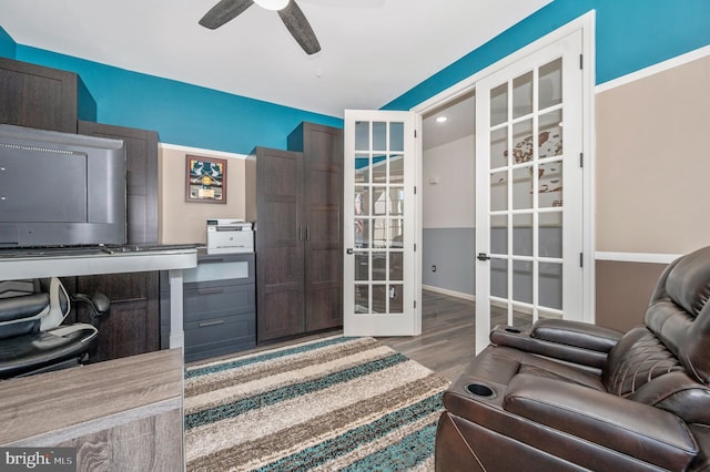 office area featuring french doors, baseboards, wood finished floors, and a ceiling fan