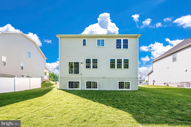 rear view of house featuring a lawn and fence