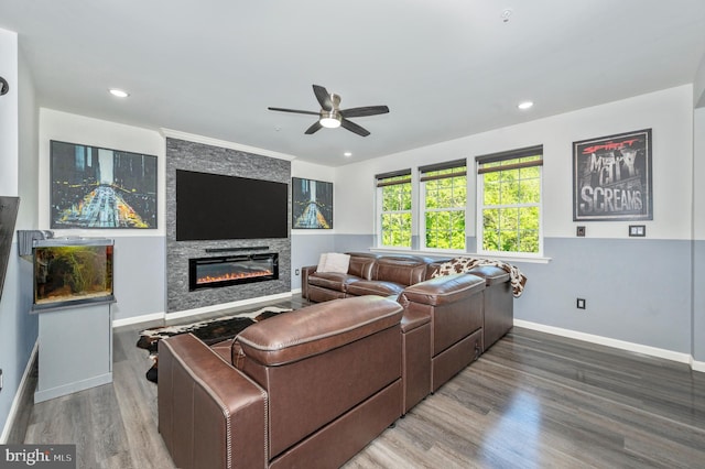 living area featuring recessed lighting, wood finished floors, baseboards, and a large fireplace