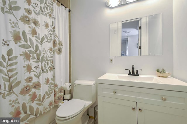 bathroom featuring curtained shower, toilet, and vanity