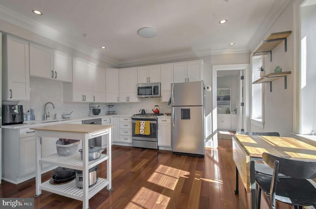 kitchen with a sink, dark wood-style floors, stainless steel appliances, crown molding, and light countertops