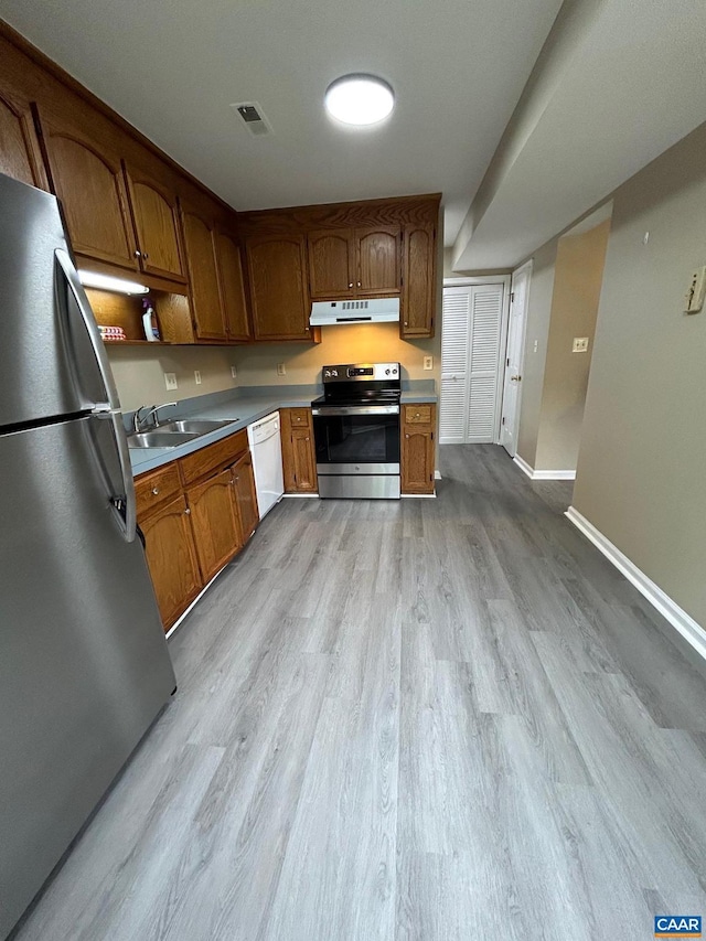 kitchen featuring visible vents, light wood-style flooring, a sink, stainless steel appliances, and under cabinet range hood