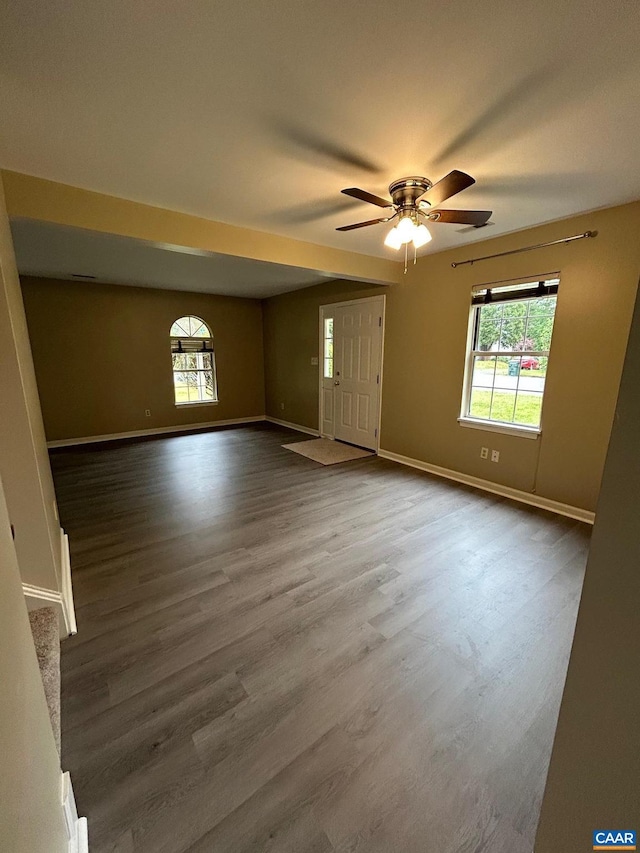 unfurnished living room featuring ceiling fan, baseboards, and wood finished floors