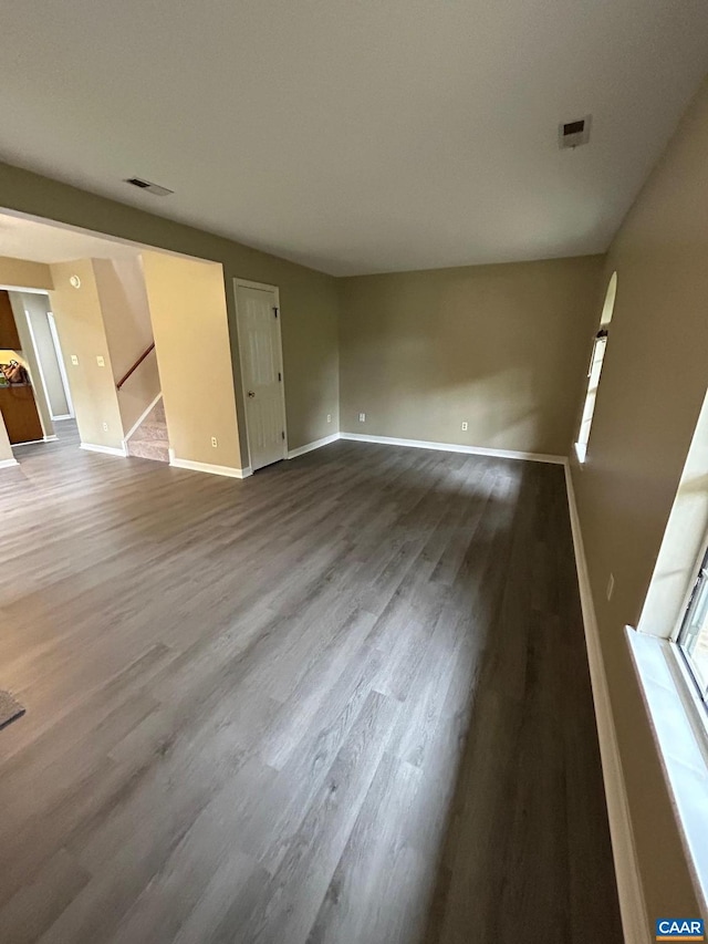 unfurnished living room featuring stairway, wood finished floors, and baseboards