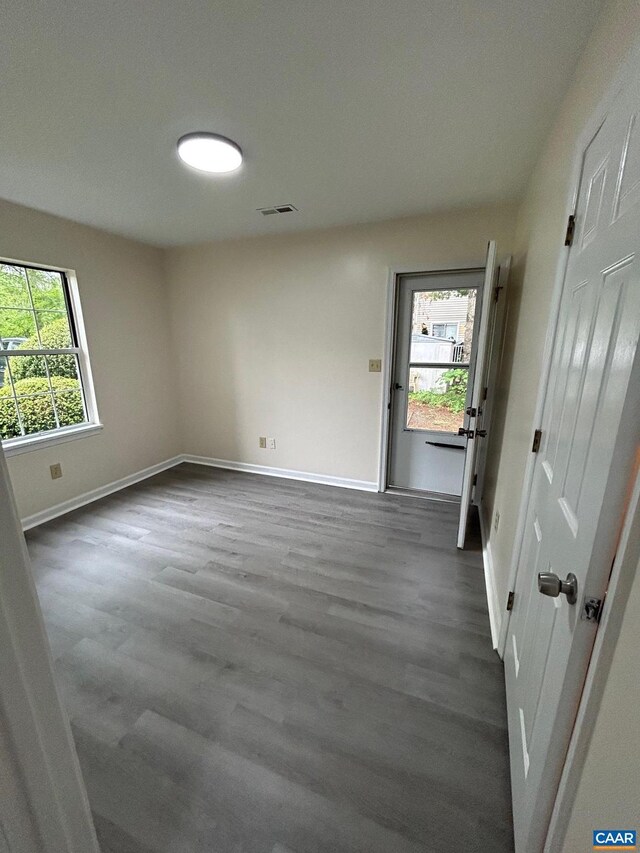 empty room with visible vents, baseboards, and dark wood-style flooring