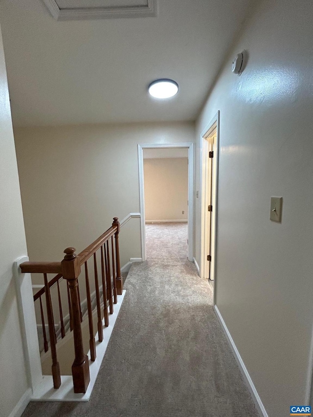 hall featuring an upstairs landing, baseboards, and carpet