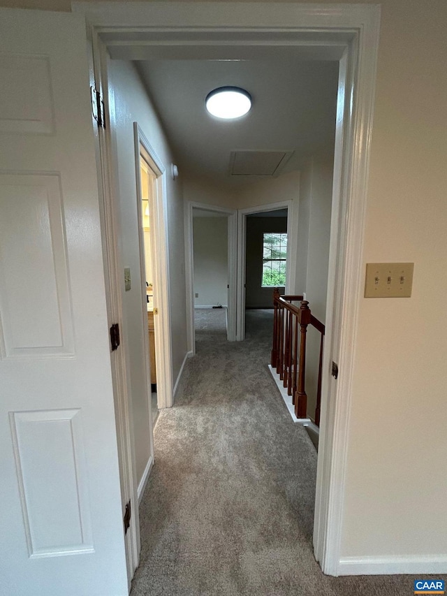 hallway with attic access, an upstairs landing, baseboards, and carpet floors