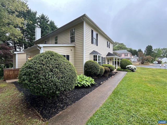 view of side of home with a chimney and a yard