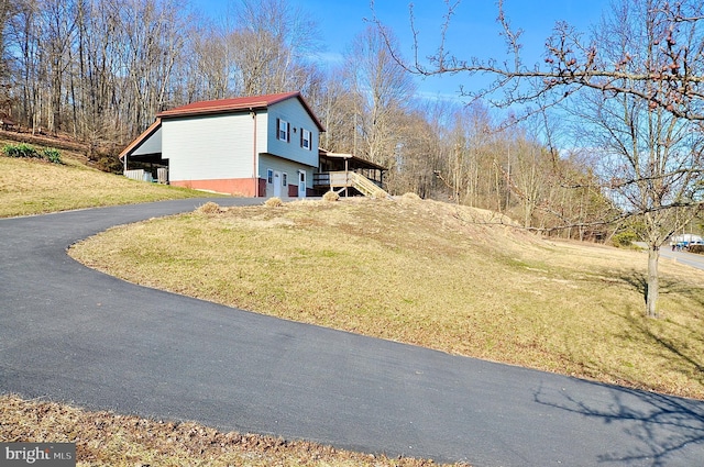 view of home's exterior featuring aphalt driveway, stairway, and a yard