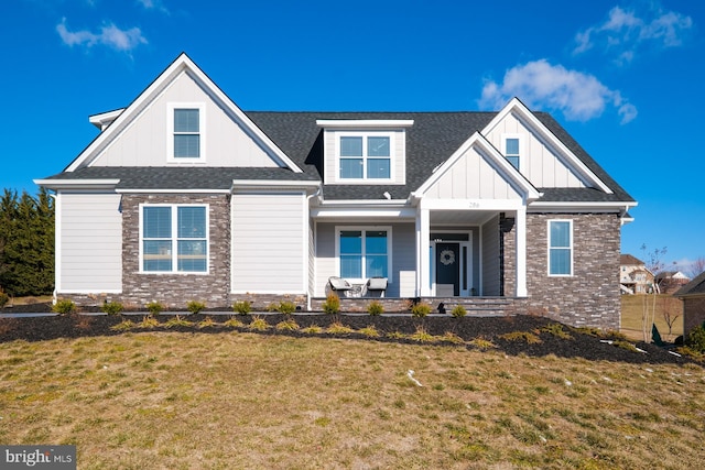 view of front of property featuring brick siding, a front lawn, covered porch, and board and batten siding