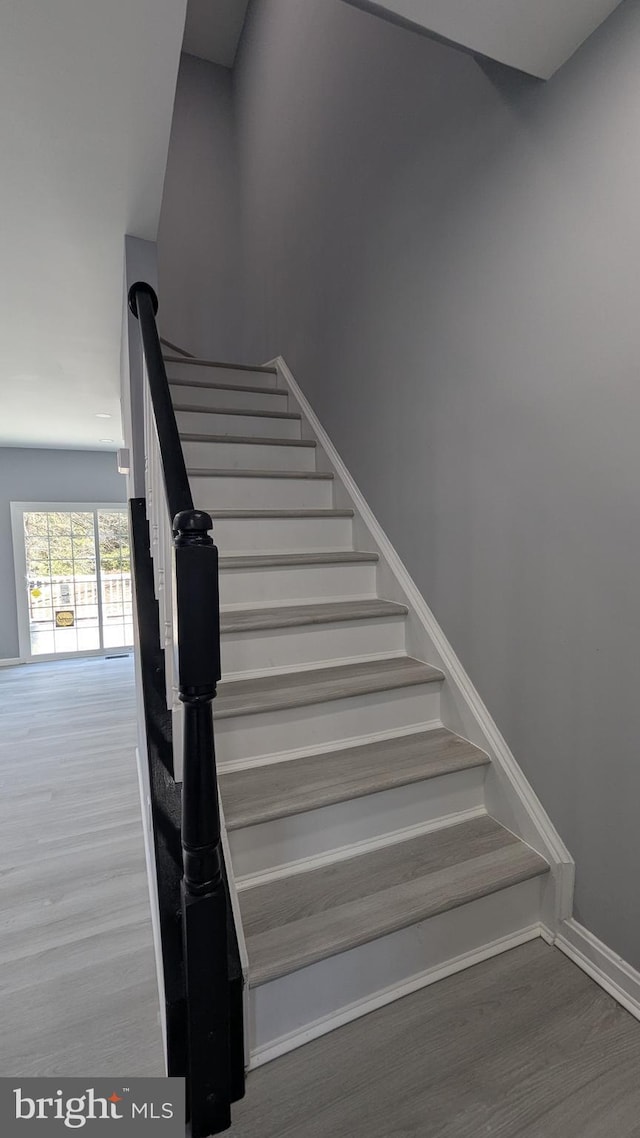 staircase with baseboards and wood finished floors