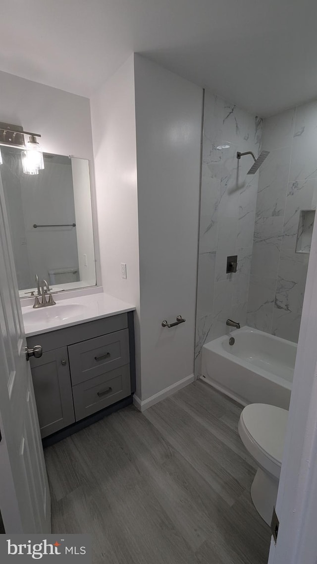 bathroom with vanity, toilet, wood finished floors, and shower / bath combination