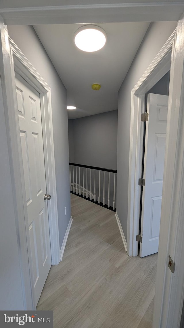 corridor featuring light wood-style floors and baseboards